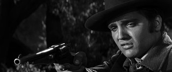 Movie still from “Love Me Tender” (1956), directed by Robert D. Webb – A man holding a gun in a black and white photo; Close Up shot, Low angle