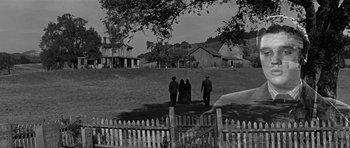 Movie still from “Love Me Tender” (1956), directed by Robert D. Webb – A group of people standing on top of a grass covered field; Extreme Wide shot, High angle