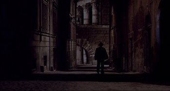 A person standing in the dark in front of an archway