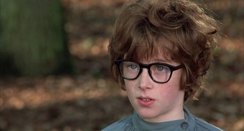 Movie still from “Love and Death” (1975), directed by Woody Allen – A young boy wearing glasses looking at the camera; Close Up shot, Over the shoulder angle