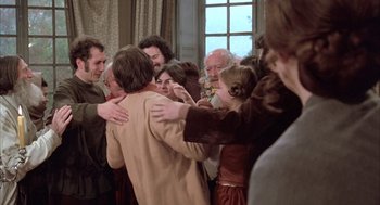 Movie still from “Love and Death” (1975), directed by Woody Allen – A group of people hugging each other in front of a window; Medium shot, Over the shoulder angle