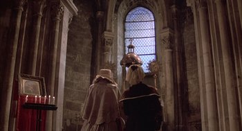 Movie still from “Love and Death” (1975), directed by Woody Allen – Two people are standing in front of a stained glass window; Wide shot, Low angle