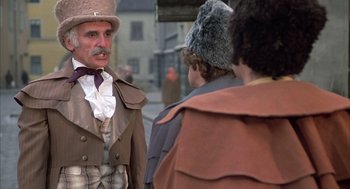 Movie still from “Love and Death” (1975), directed by Woody Allen – An old man in a hat is standing next to two other people; Medium shot, Low angle