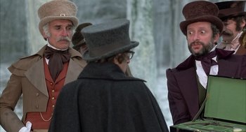 Movie still from “Love and Death” (1975), directed by Woody Allen – A group of people standing next to each other wearing hats; Medium shot, Over the shoulder angle