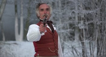 Movie still from “Love and Death” (1975), directed by Woody Allen – A man in a red vest holding a gun in a snowy forest; Medium shot, Low angle