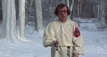 Movie still from “Love and Death” (1975), directed by Woody Allen – A man in a white shirt holding a knife in the snow; Medium shot, Over the shoulder angle