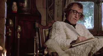 Movie still from “Love and Death” (1975), directed by Woody Allen – A man sitting in a chair reading a book; Medium shot, Over the shoulder angle