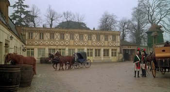 Movie still from “Love and Death” (1975), directed by Woody Allen – Two horses pulling a carriage down a dirt road in front of a building; Extreme Wide shot, High angle