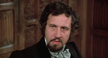 Movie still from “Love and Death” (1975), directed by Woody Allen – A person wearing a suit and a bow tie; Close Up shot, Over the shoulder angle