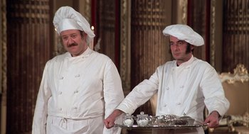 Movie still from “Love and Death” (1975), directed by Woody Allen – A couple of men standing next to each other; Medium shot, Low angle