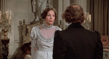 Movie still from “Love and Death” (1975), directed by Woody Allen – A woman in a white dress and a man in a black suit stand in front of a statue; Medium shot, Over the shoulder angle