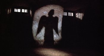 Movie still from “Love and Death” (1975), directed by Woody Allen – A shadow of an angel on a brick wall; Wide shot, Low angle