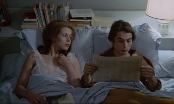 Movie still from “Love on the Run” (1979), directed by François Truffaut – A man and a woman in a bed reading a newspaper; Medium shot, High angle