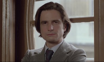 Movie still from “Love on the Run” (1979), directed by François Truffaut – A person wearing a suit and tie; Close Up shot, Low angle