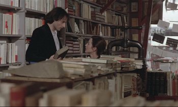 Movie still from “Love on the Run” (1979), directed by François Truffaut – A man and a woman are looking at each other in a library; Medium shot, Over the shoulder angle