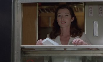 Movie still from “Love on the Run” (1979), directed by François Truffaut – A woman standing in front of a window holding papers; Medium shot, Low angle