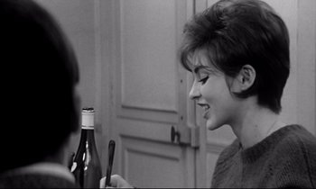 Movie still from “Love on the Run” (1979), directed by François Truffaut – A woman holding a bottle of wine in front of another woman in a room; Close Up shot, Over the shoulder angle