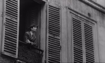 Movie still from “Love on the Run” (1979), directed by François Truffaut – A black and white photo of a man looking out of an open window; Medium shot, Low angle