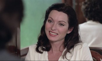 Movie still from “Love on the Run” (1979), directed by François Truffaut – A person sitting in front of a camera smiling; Close Up shot, Over the shoulder angle