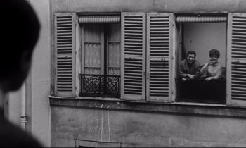 Movie still from “Love on the Run” (1979), directed by François Truffaut – A black and white photo of a man looking out of a window; Wide shot, Low angle