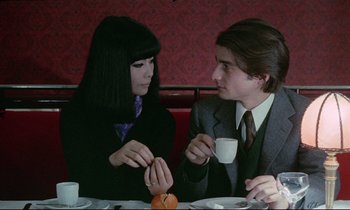 Movie still from “Love on the Run” (1979), directed by François Truffaut – A man and a woman sitting at a table with a cup of coffee; Medium shot, High angle