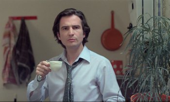 Movie still from “Love on the Run” (1979), directed by François Truffaut – A man holding a coffee cup while wearing a tie; Close Up shot, Low angle