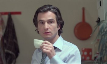 Movie still from “Love on the Run” (1979), directed by François Truffaut – A man holding a coffee cup in his hand; Close Up shot, Over the shoulder angle