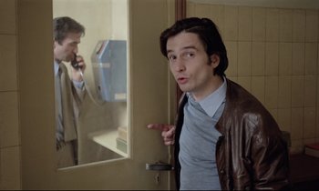 Movie still from “Love on the Run” (1979), directed by François Truffaut – A man in a brown jacket is looking at himself in the mirror; Medium shot, Over the shoulder angle