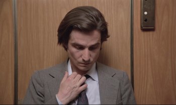 Movie still from “Love on the Run” (1979), directed by François Truffaut – A man in a suit and tie is holding his tie; Close Up shot, Low angle