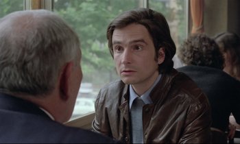 Movie still from “Love on the Run” (1979), directed by François Truffaut – A man in a leather jacket talking to another man in front of a window; Close Up shot, Over the shoulder angle