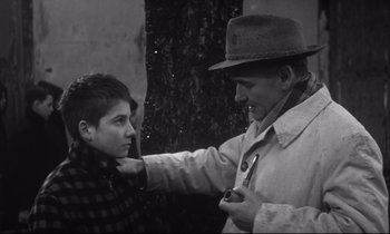 Movie still from “Love on the Run” (1979), directed by François Truffaut – An older man putting a tie on a young boy's head; Medium shot, Over the shoulder angle