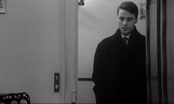 Movie still from “Love on the Run” (1979), directed by François Truffaut – A man standing in front of an open door; Medium shot, Over the shoulder angle
