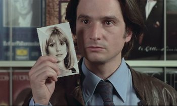 Movie still from “Love on the Run” (1979), directed by François Truffaut – A man holding up a picture of a woman; Close Up shot, High angle