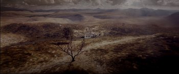 Movie still from “Loveless” (2017), directed by Andrey Zvyagintsev – An aerial view of an empty field with a tree in the foreground; Extreme Wide shot, High angle