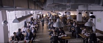 Movie still from “Loveless” (2017), directed by Andrey Zvyagintsev – People are sitting at tables in an industrial style dining hall; Wide shot, High angle