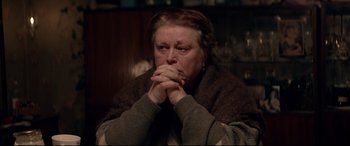 Movie still from “Loveless” (2017), directed by Andrey Zvyagintsev – An older woman sitting on a couch with her hands folded to her chest; Close Up shot, Over the shoulder angle