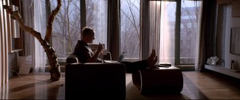 Movie still from “Loveless” (2017), directed by Andrey Zvyagintsev – A person sitting on a couch with a laptop; Wide shot, Low angle
