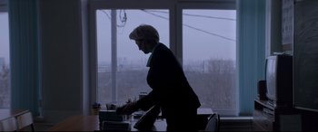 Movie still from “Loveless” (2017), directed by Andrey Zvyagintsev – A woman standing at a table in front of a large window; Medium shot, Over the shoulder angle
