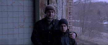 Movie still from “Loveless” (2017), directed by Andrey Zvyagintsev – A man standing next to a young boy in winter clothing; Medium shot, Low angle