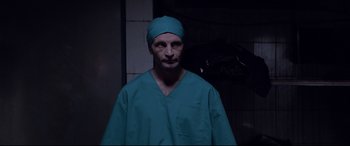 Movie still from “Loveless” (2017), directed by Andrey Zvyagintsev – A man wearing a green surgical gown and a blue hat; Medium shot, Low angle
