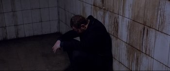 Movie still from “Loveless” (2017), directed by Andrey Zvyagintsev – A man sitting on the ground with his head down; Medium shot, High angle