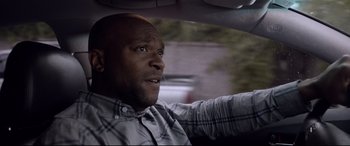 A man in a plaid shirt driving in a car