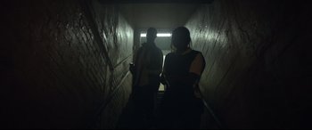 A man and a woman standing in a dark hallway