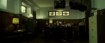 Movie still from “Lucky Number Slevin” (2006), directed by Paul McGuigan – A man sitting at a table in a dark room; Wide shot, Low angle