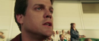 Movie still from “Lucky Number Slevin” (2006), directed by Paul McGuigan – A man's face in front of a group of people; Close Up shot, Low angle