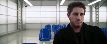 Movie still from “Lucky Number Slevin” (2006), directed by Paul McGuigan – A man sitting in front of a group of blue chairs; Close Up shot, Over the shoulder angle
