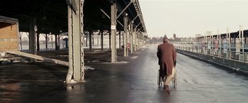 Movie still from “Lucky Number Slevin” (2006), directed by Paul McGuigan – An old man in a wheelchair walking down the street; Wide shot, Over the shoulder angle