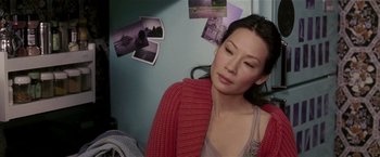 Movie still from “Lucky Number Slevin” (2006), directed by Paul McGuigan – A woman in a red sweater is sitting in front of a wall; Close Up shot, High angle
