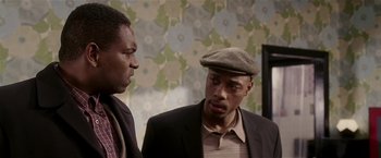 Movie still from “Lucky Number Slevin” (2006), directed by Paul McGuigan – Two men standing next to each other in front of a floral wallpaper; Close Up shot, Over the shoulder angle