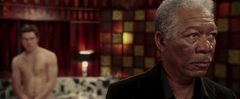 Movie still from “Lucky Number Slevin” (2006), directed by Paul McGuigan – An older man wearing a suit and tie in front of a tiled wall; Close Up shot, Over the shoulder angle